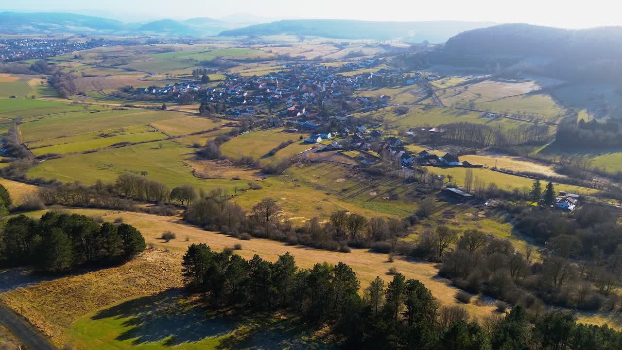 una vista aérea serena de una exuberante aldea rural en medio de colinas onduladas