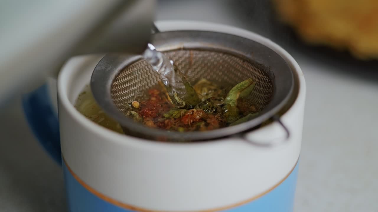 Boiling water being poured over herbs for calming, natural homemade tea brew