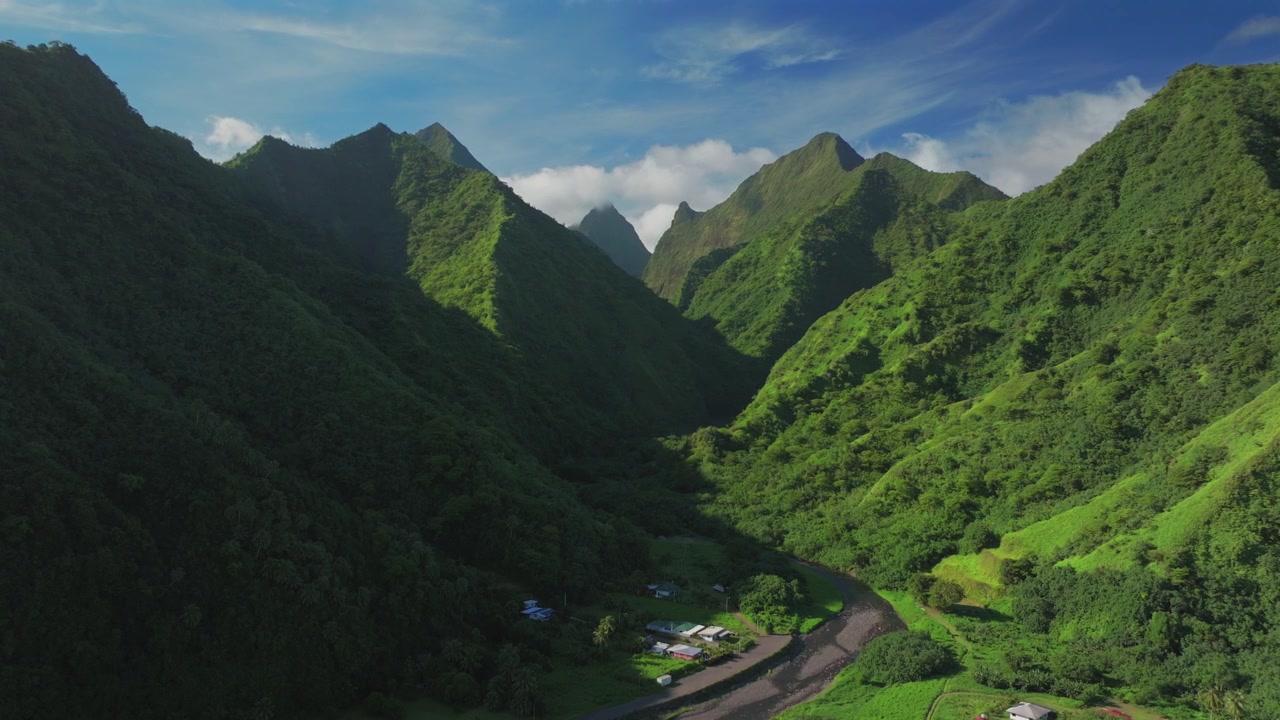 Enden af vejen Vaiau-floden Balley Teahupo'o Tahiti Sydlige Stillehavsø Fransk Polynesien luftdrone vulkanbjerg tårnhøje jungletinder solrig eftermiddag blå himmel dis skyer cirkel højre.
