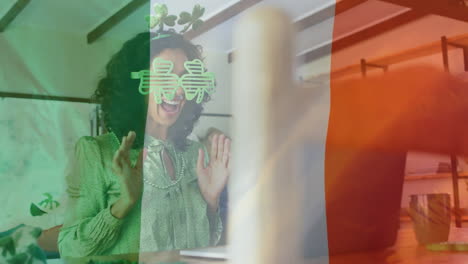 animation of flag of ireland and biracial woman in shamrock glasses celebrating st patrick's day