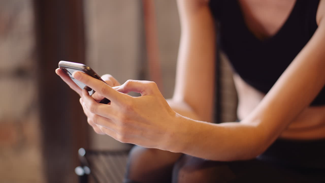 Bella atleta che invia messaggi tramite cellulare durante la pausa in palestra 1