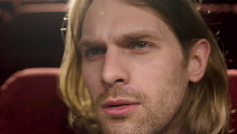 close up view of blond man watching a movie in the cinema