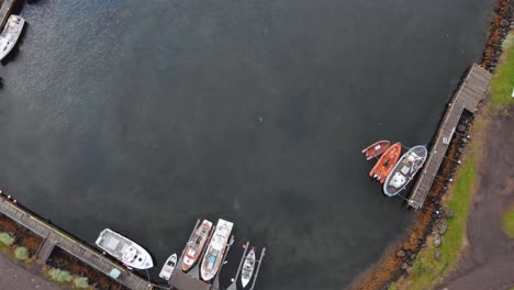 Top-down-aerial-of-boast-in-a-fjord-of-Seydisfjordur-town-in-Iceland