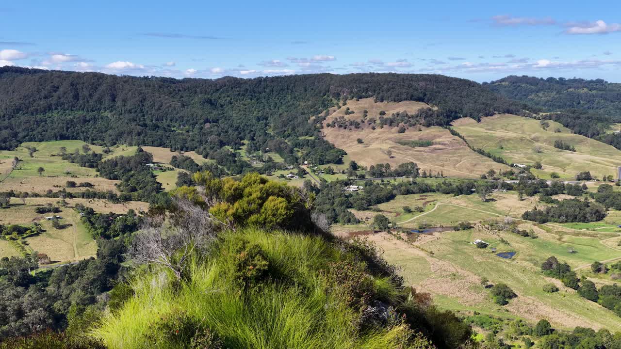 Panoramic view of lush green landscapes and rocky formations under clear blue skies in Nimbin, Australia