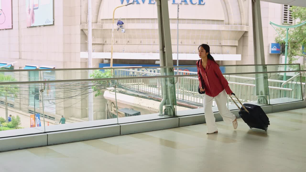 Woman hurrying with luggage on footbridge in city