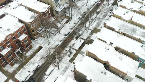 aerial, red car turns onto urban road during winter