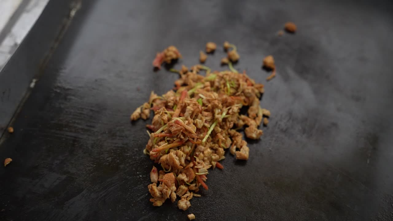 Spiced chicken shawarma filling with herbs being cooked on a flat griddle surface. Pakistan