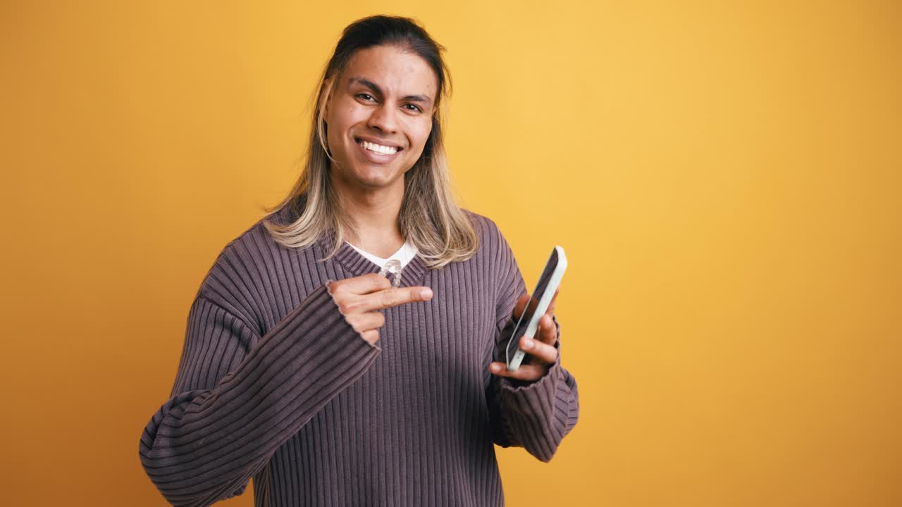 Joven sonriente sosteniendo un alineador dental transparente y un smartphone