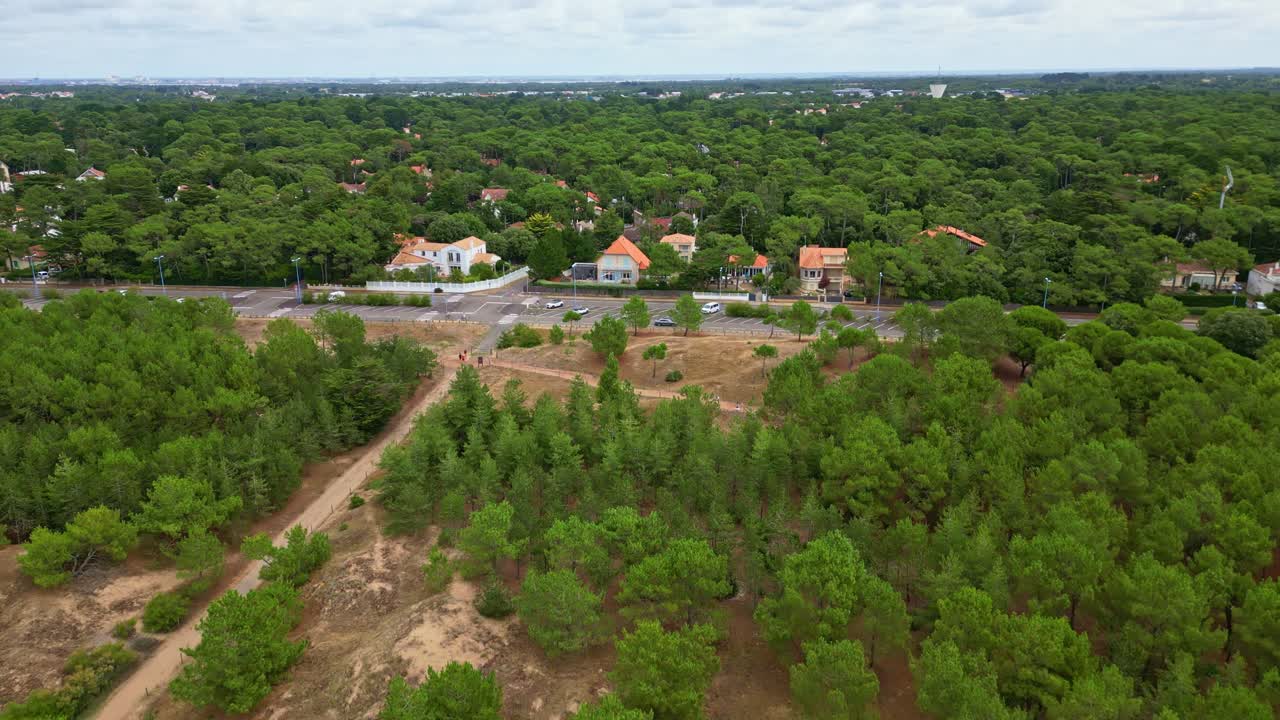Backward drone movement of small residential houses surrounded by dense green forest in summer, Saint-Brevin-les-Pins, Loire-Atlantique, France