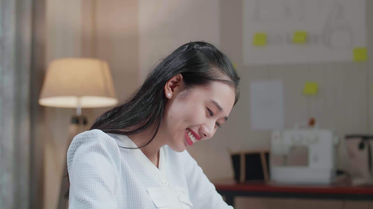 사무실에서 노트북으로 작업하는 동안 레이아웃을 가진 아시아 여성 디자이너의 클로즈업 본드 미소 카메라