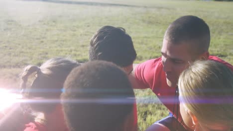 Animación-De-Puntos-De-Luz-Sobre-Diversos-Escolares-Haciendo-Equipo-Con-El-Entrenador-En-El-Estadio.