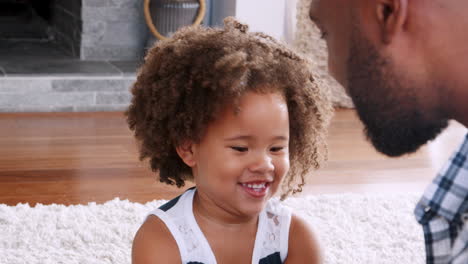 Young-black-girl-playing-instrument-with-dad-in-sitting-room