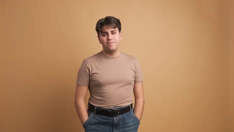 cheerful man in casual clothes standing in beige studio
