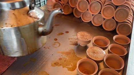 In-several-Kulhad,-a-cook-pours-hot-tea-to-sell-on-the-streets-of-Kolkata,-India