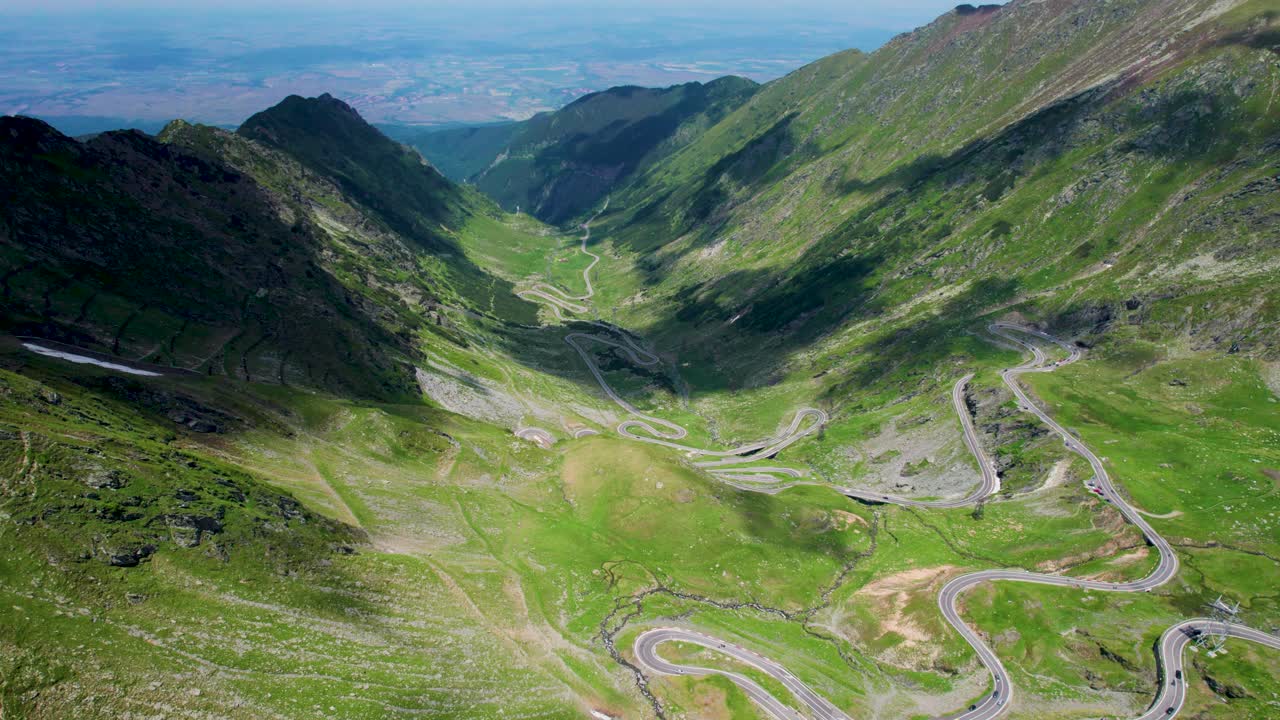 hermosa vista aérea de la carretera de montaña transfagarasan que cruza las montañas de los cárpatos en rumania, vista aérea de una hermosa cordillera con picos altos, nubes espesas y esponjosas