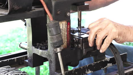 A-man-using-a-mechanical-hole-punch-to-punch-holes-into-some-rubber