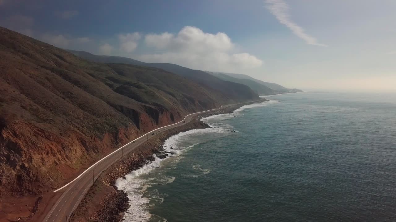 Inquadratura aerea super ampia e discendente di una costa e di un'autostrada costiera. 4K