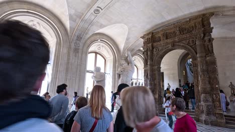 crowd exploring sculptures in louvre museum, paris