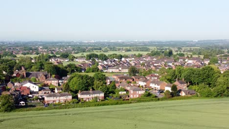 Toma-Aérea-Panorámica-De-Las-Idílicas-Tierras-De-Cultivo-De-La-Aldea-De-Cronton-En-El-Reino-Unido-Inglaterra-Con-Vistas-Al-Hermoso-Campo-Con-Casas-Residenciales