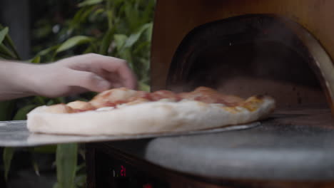 Chef-takes-out-Neapolitan-pizza-and-turns-it,-and-puts-back-inside-oven