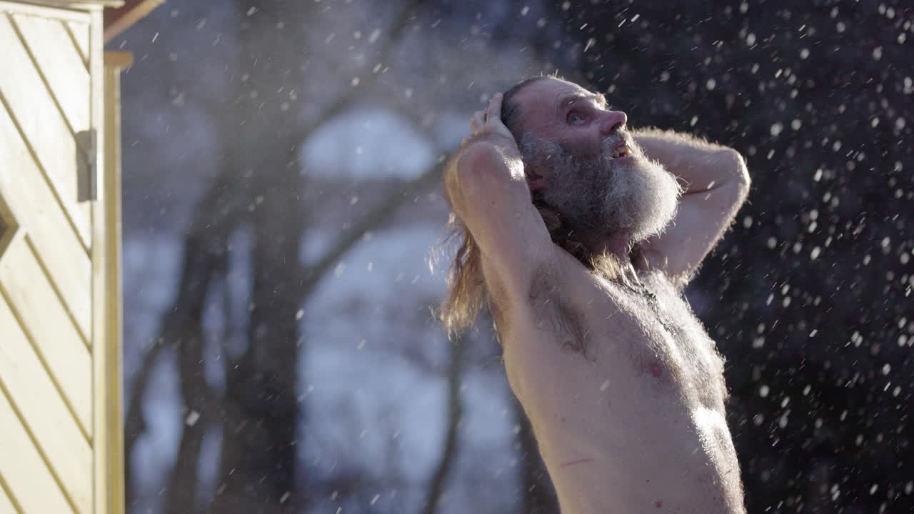 Steam rise off sweaty skin of man after sauna looking up in prayer in snowfall