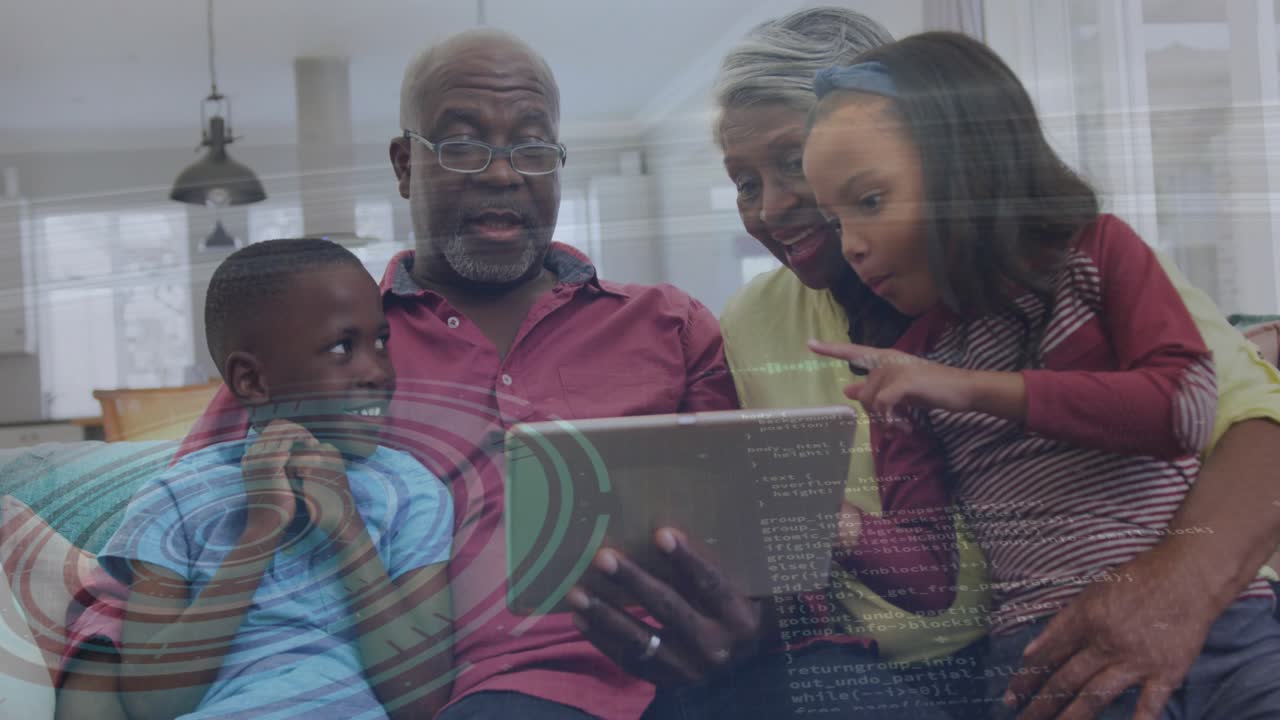 Anziani e bambini sul divano, una bambina tocca il tablet per mostrare, attivando effetti tecnologici, la famiglia sorride.