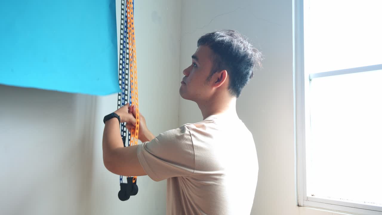 Young photographer lowers blue background setting up photo shoot in studio
