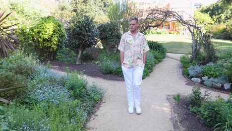 Joven-Varón-Blanco-Caucásico-En-Camisa-Hawain-Caminando-Por-El-Tranquilo-Jardín_cámara-Lenta