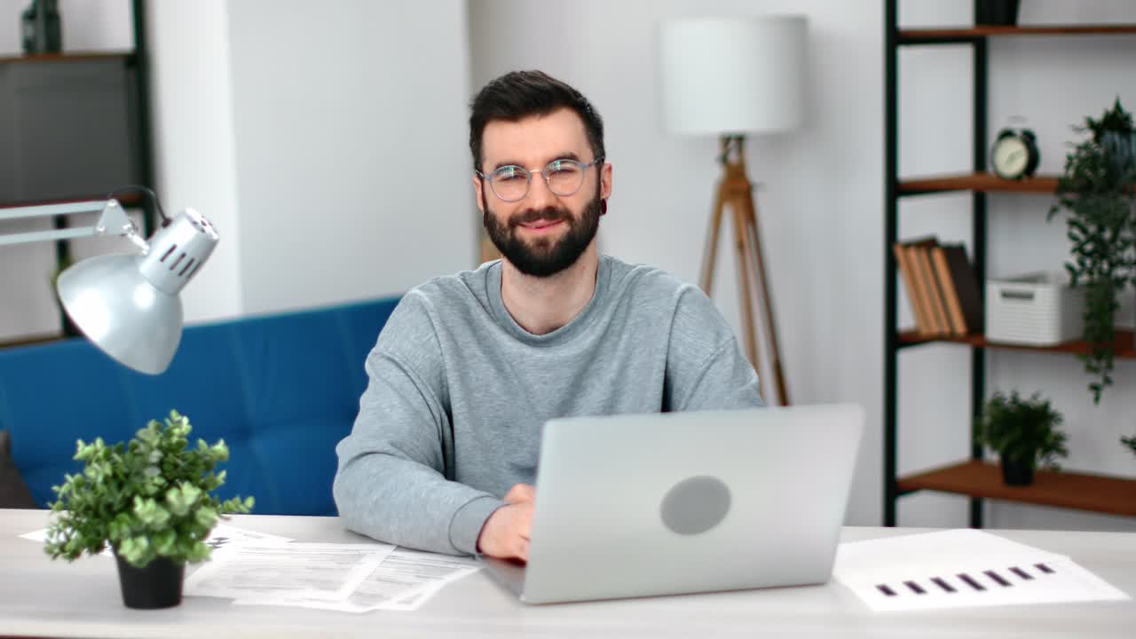 retrato moderno barbudo sonriente hombre de negocios europeo posando en una cómoda oficina lugar de trabajo portátil