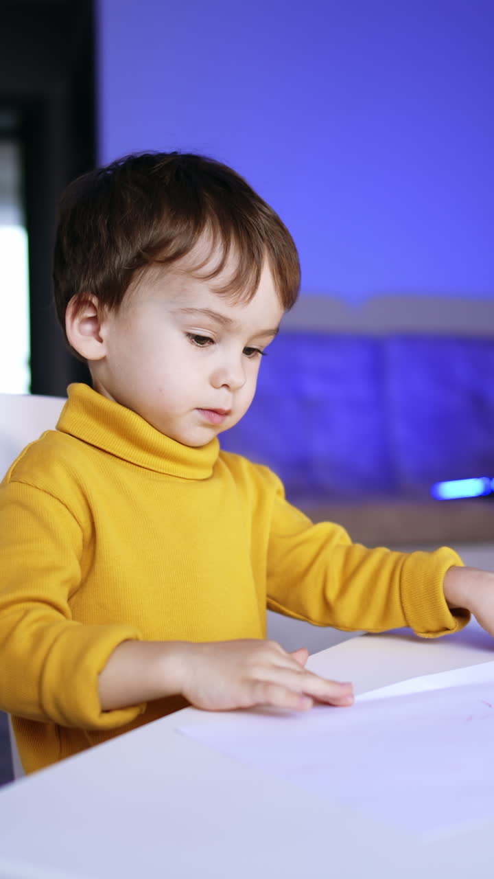 Charming little baby sitting at the desk drawing