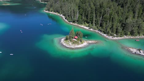 orange red hut cabin in the lake surrounded by tree in a little island in eibsee bayern deutschland by colorful beautiful wonderful lake water turquoise green blue shallow depth water yacht boat enjoy