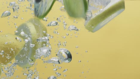 Video-of-slices-of-lime-and-lemon-falling-into-water-with-copy-space-on-yellow-background