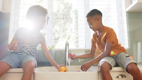 children washing fruit together in kitchen sink, enjoying african american family time