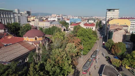 aerial ascending shot beside trees with reveal of cityscape view of sofia, bulgaria