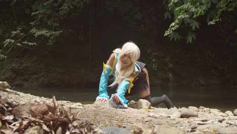 sexy lucy cosplayer on her knees picking up her keys from the ground with a river flowing in the background