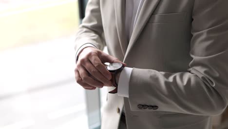 Elegant-gentleman-in-a-suit-tuxedo-adjusting-classic-brown-wristwatch