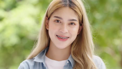 close-up portrait of pretty asian student smiling standing alone and looking at camera,positive emotions concept.