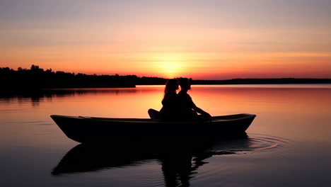 couple in a boat on a lake at sunset