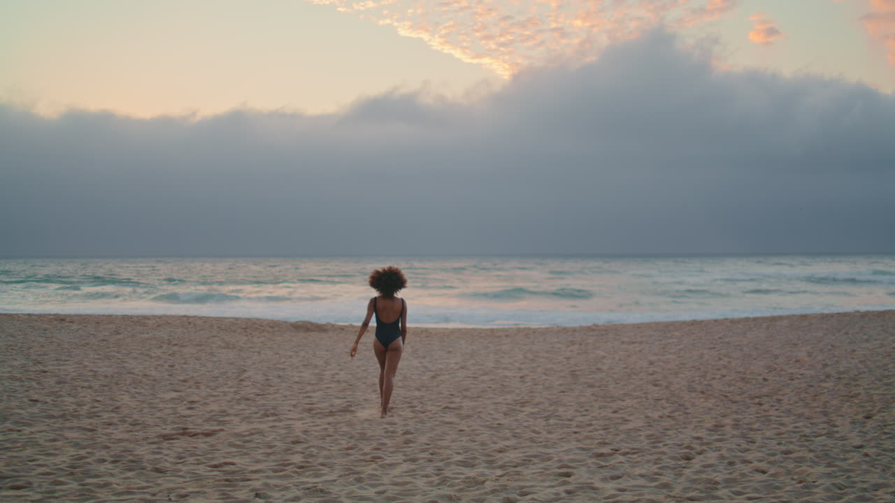 편안한 여성은 바가에서 바다의 파도 근처의 모래를 고 즐기고 있습니다.