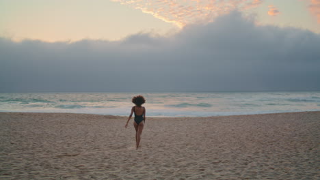 Una-Mujer-Relajada-Disfruta-De-La-Orilla-Del-Mar-Caminando-Sobre-La-Arena-Cerca-De-La-Vista-Posterior-De-Las-Olas-Del-Océano.