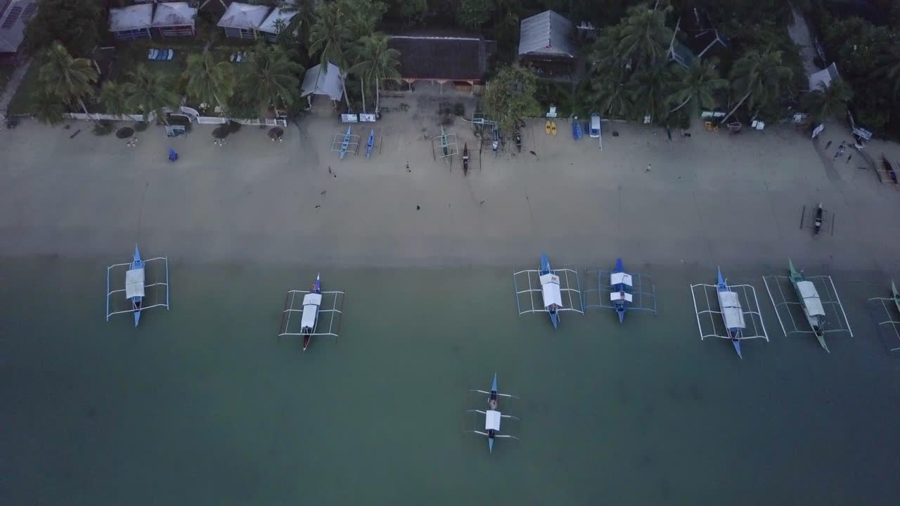 필리핀의 이른 아침 해변 옆 어촌의 공중 전망 - 카메라 받침대가 보트와 바다로 기울어져 있습니다.