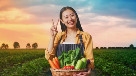 asian female farmer with vegetable basket showing gesture peace and smiling while standing in field