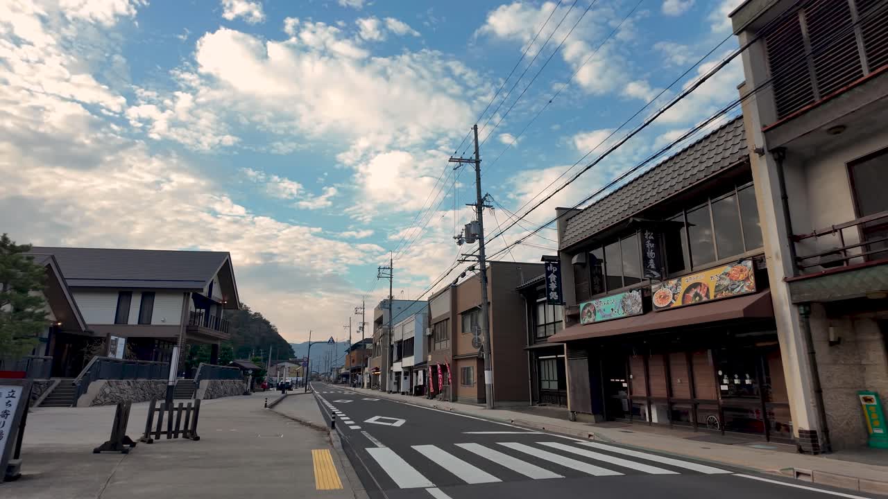 Empty street with traditional Japanese architecture and restaurants outside Amanohashidate Station in Kyoto, Japan, under a beautiful cloudy sky