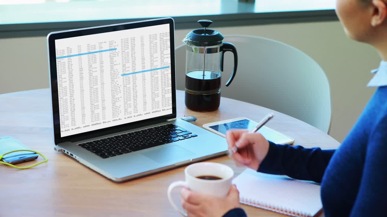Caucasian woman sitting at desk processing on laptop and making notes