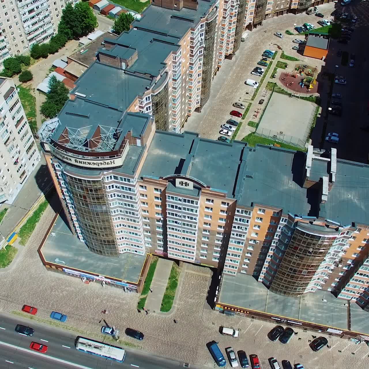 Afordable apartment buildings in the city. Tall skyscrapers with colorful facades with parking space for cars and a children playground in the yard. Aerial view.