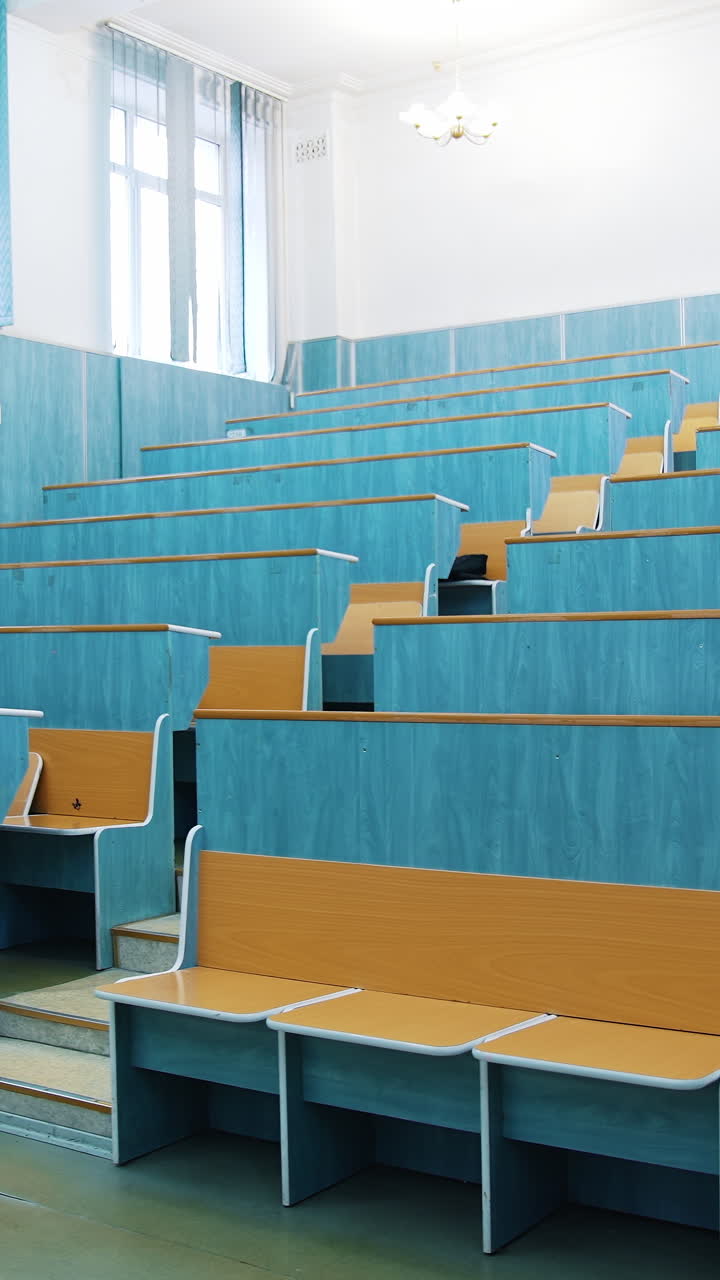 Modern auditorium with wooden desks without people. Large meeting hall with empty desks. Nobody in lecture hall in the university during quarantine. Vertical video