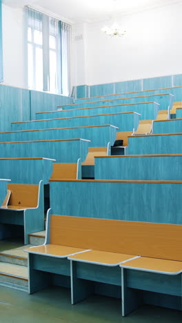 modern auditorium with wooden desks without people. large meeting hall with empty desks. nobody in lecture hall in the university during quarantine. vertical video