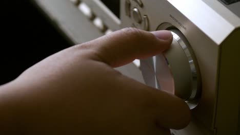 men's hands adjusting volume control of the amplifier form the home theater system with the adjust button for broadcasting and music