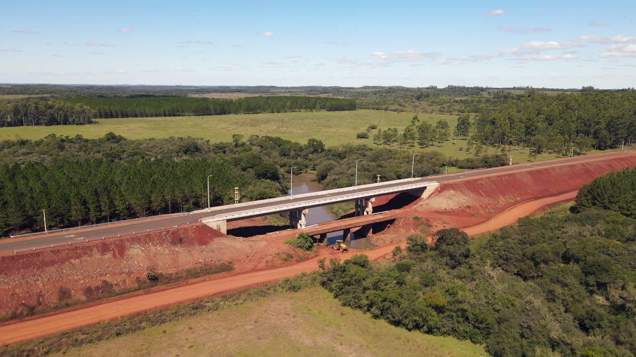avión no tripulado se acerca a un puente en un sitio de construcción rural