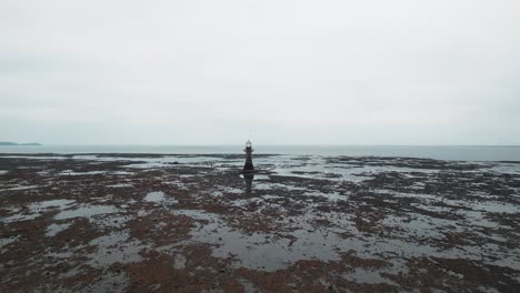 AERIAL:-Low-slow-fly-towards-Whiteford-Lighthouse-at-low-tide,-Whiteford,-4k-Drone